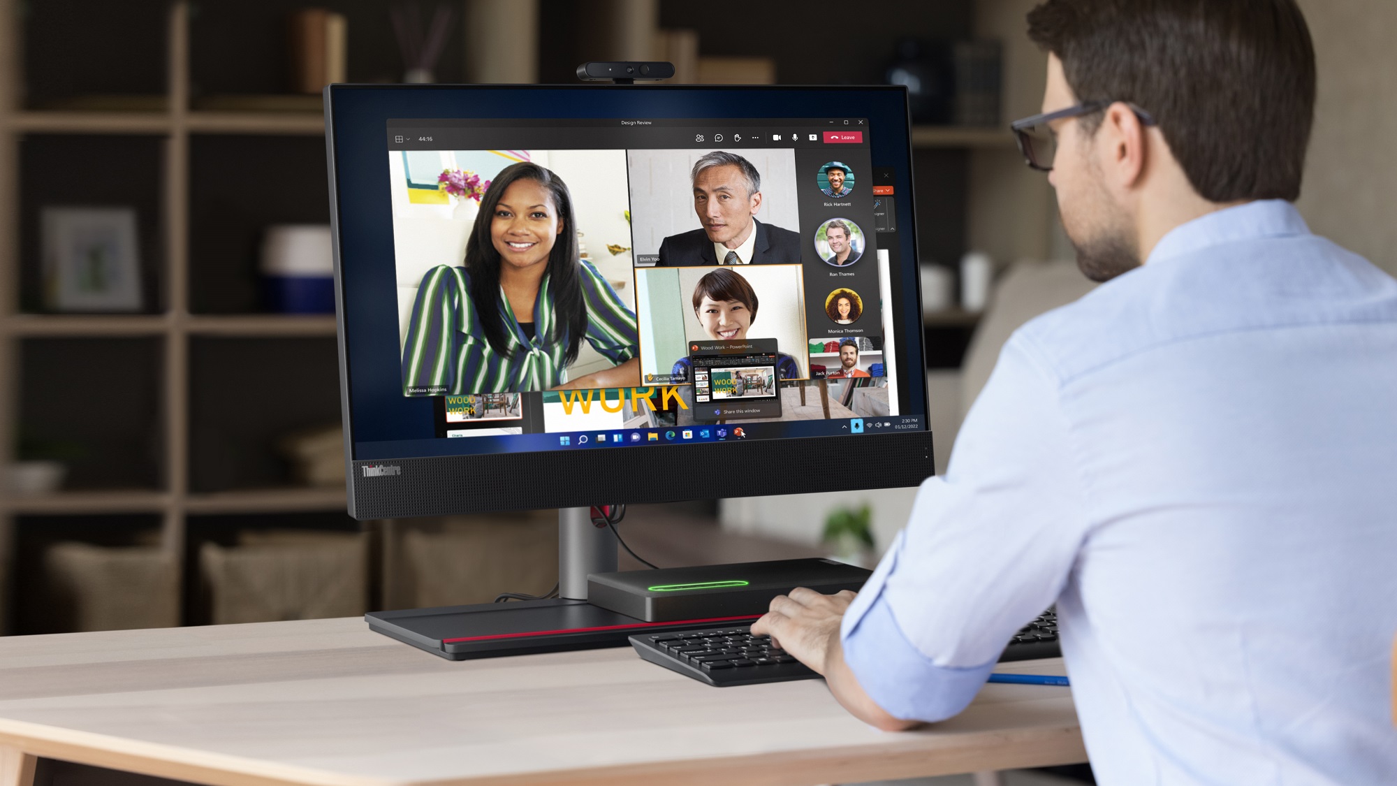 Man sitting in front of ThinkCentre AIO on a Teams video meeting with several faces on screen