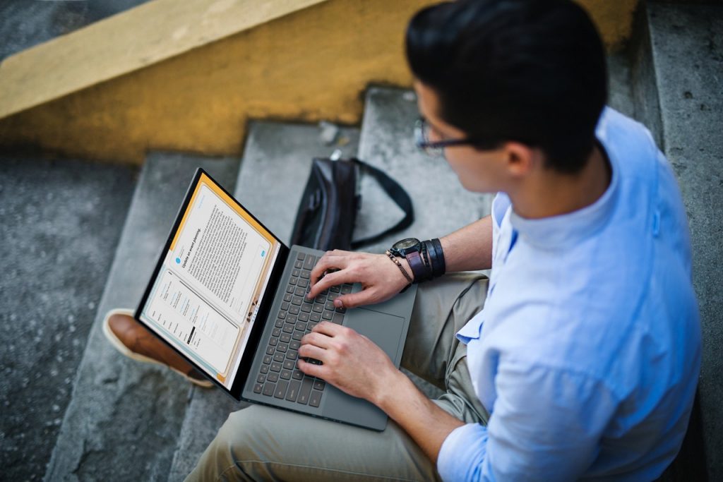 Man sitting on steps typing on a laptop