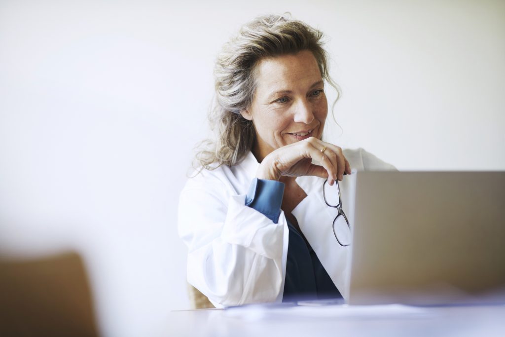 Female medical worker looks at laptop