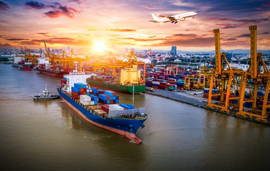 Plane flying over cargo ship filled with boxes