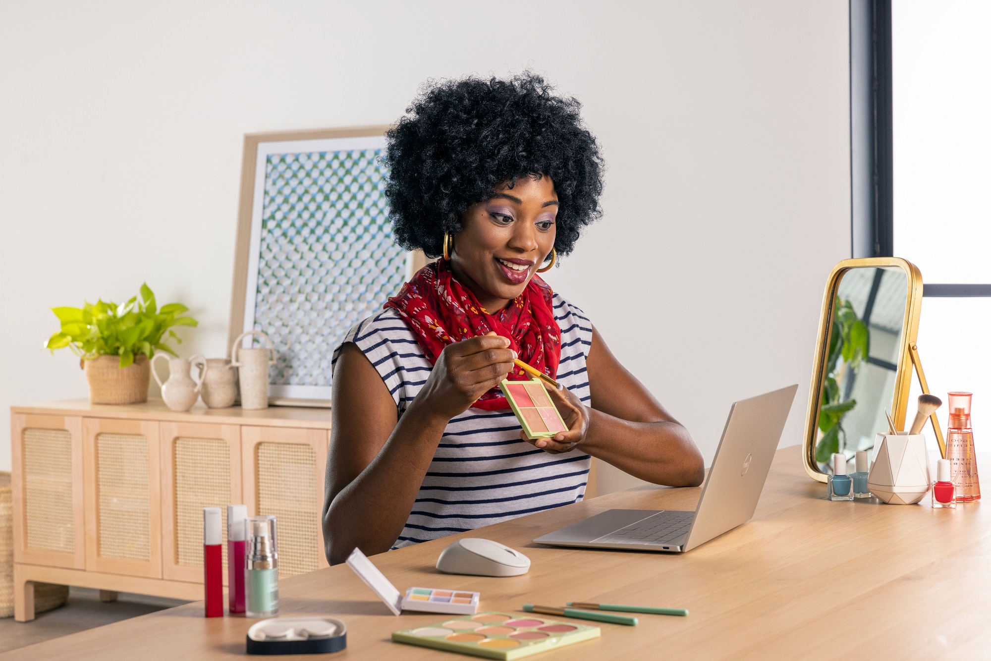 Black woman showing makeup palette to camera on Dell laptop