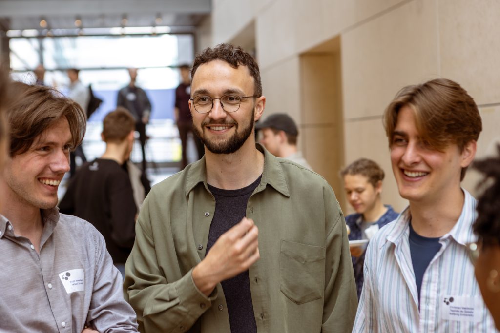 Three students on the team standing and talking in an open indoor area