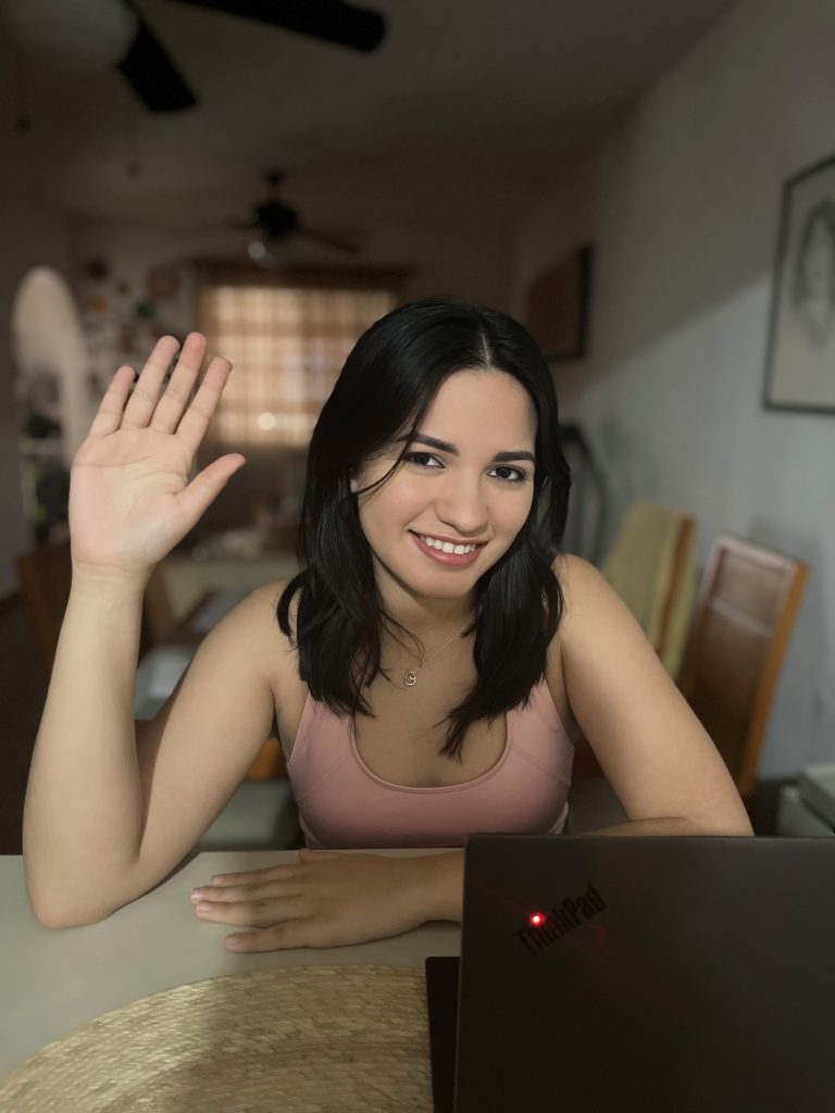 Women looking at camera holding up her left hand and arm, while sitting