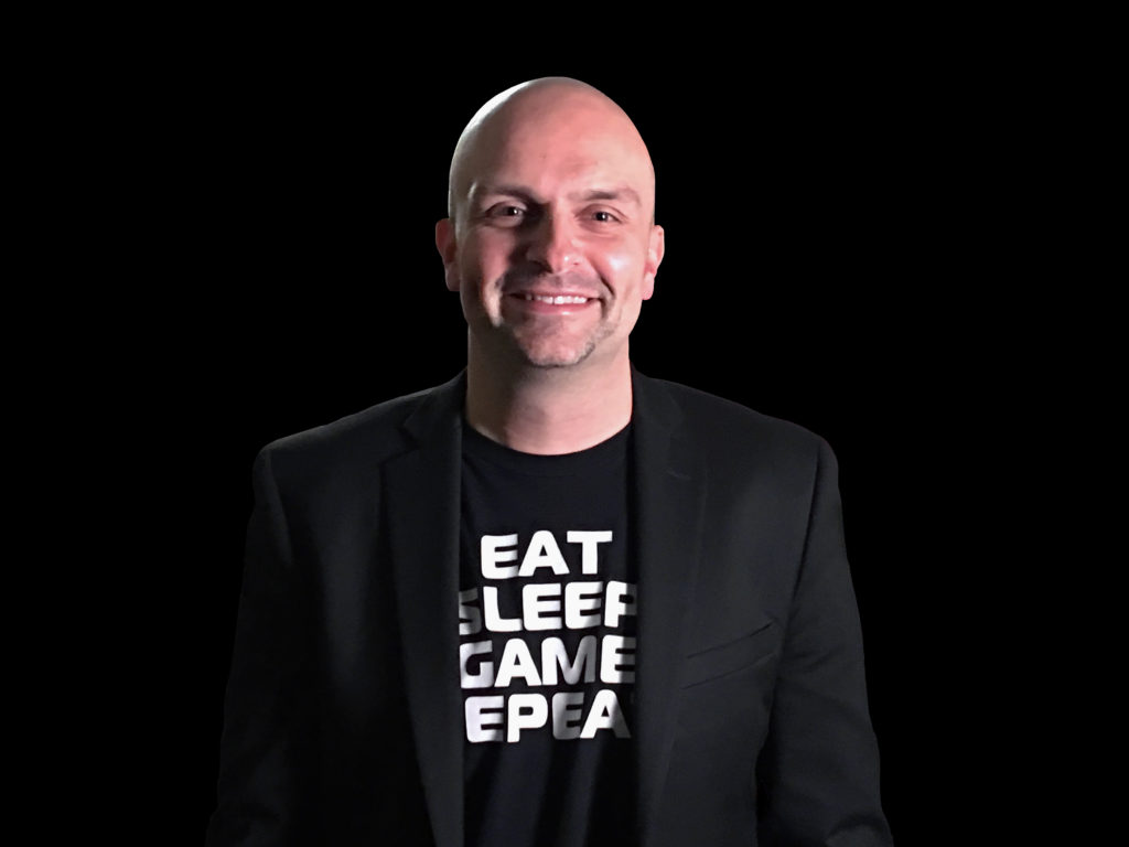 Photo of ORIGIN PC co-founder Kevin Wasielewski wearing a black t-shirt and black jacket against a black background