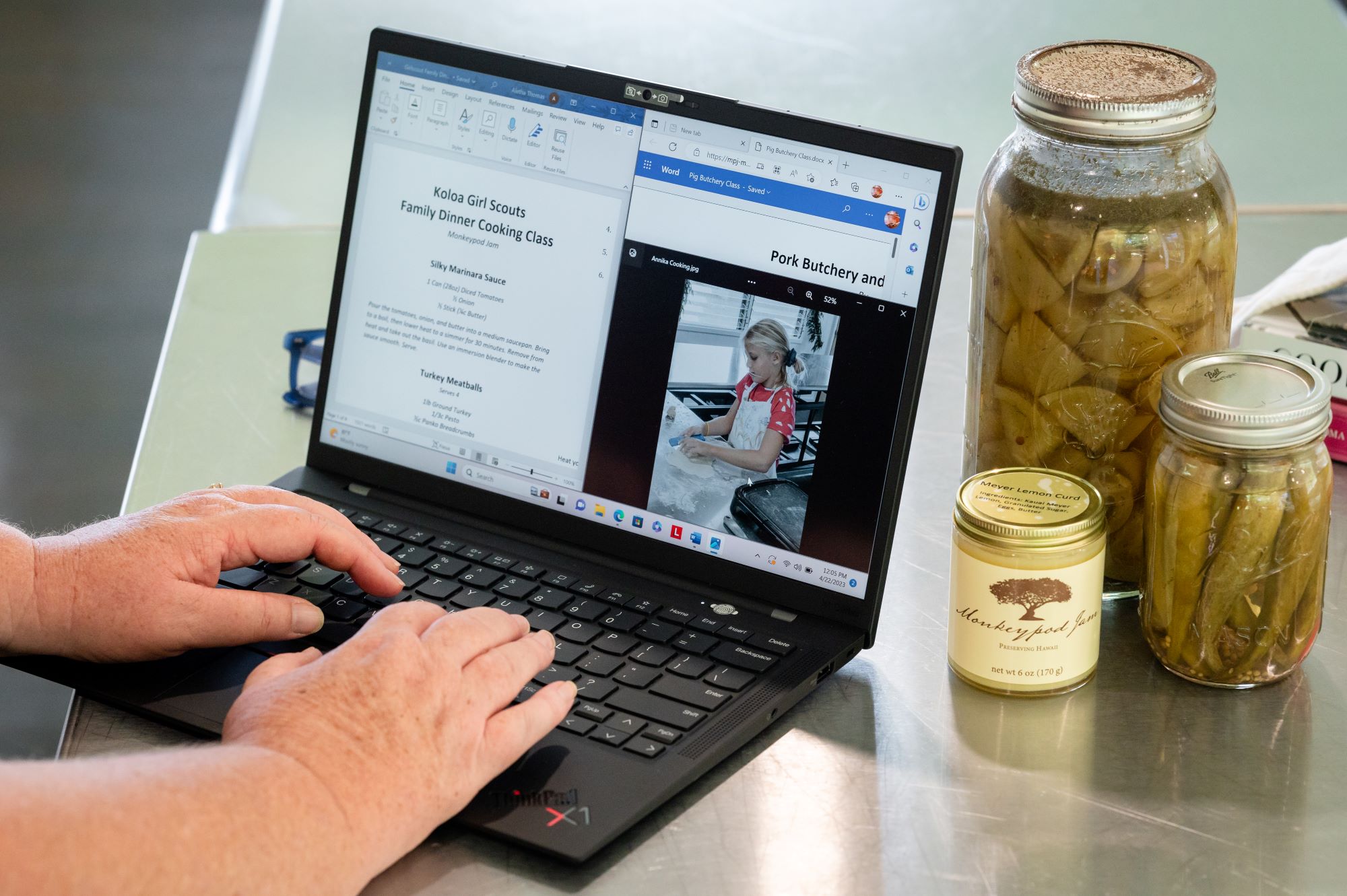 Woman typing on her Lenovo laptop, as seen from behind her